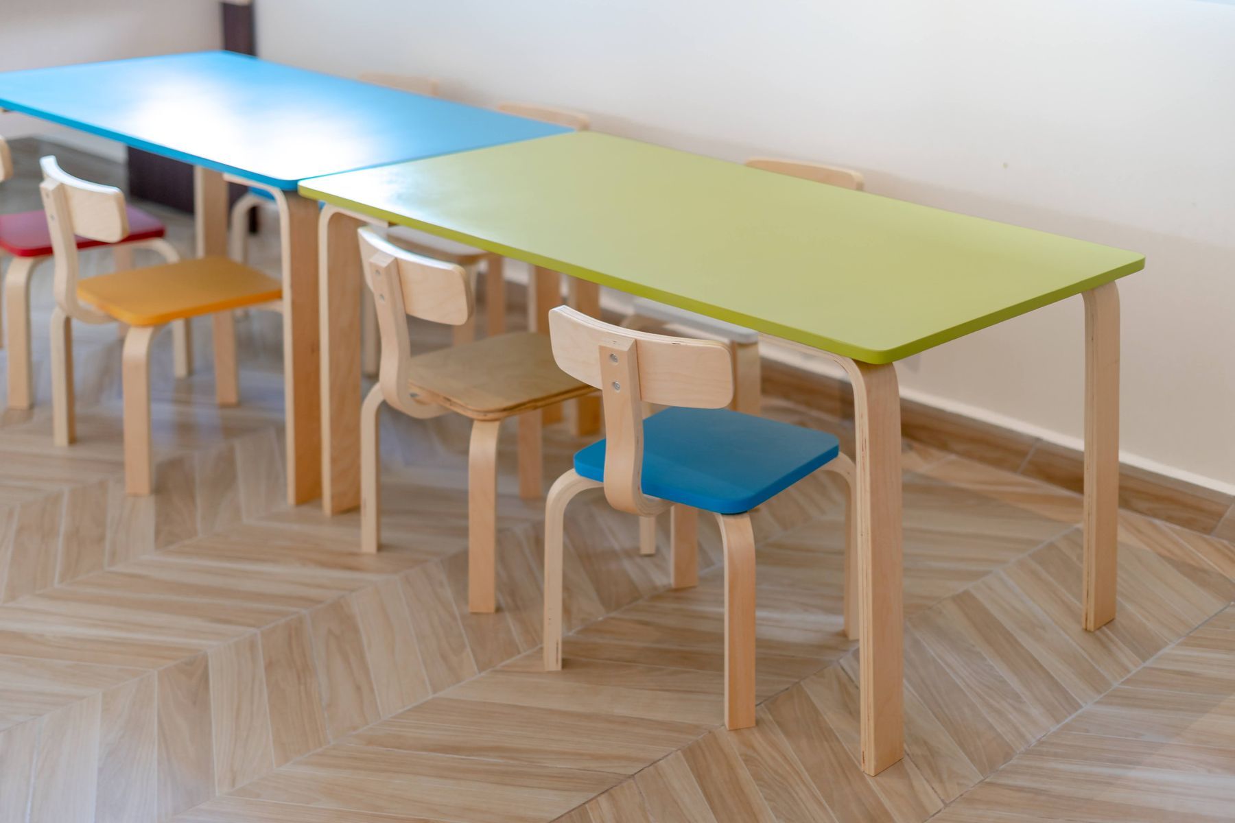Child-sized tables and chairs in a clean, bright daycare classroom