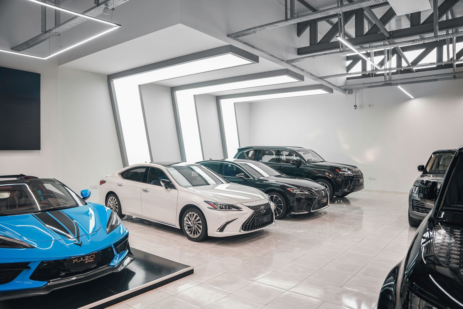 Dealership showroom with vehicles on a polished tile floor under full-height glass